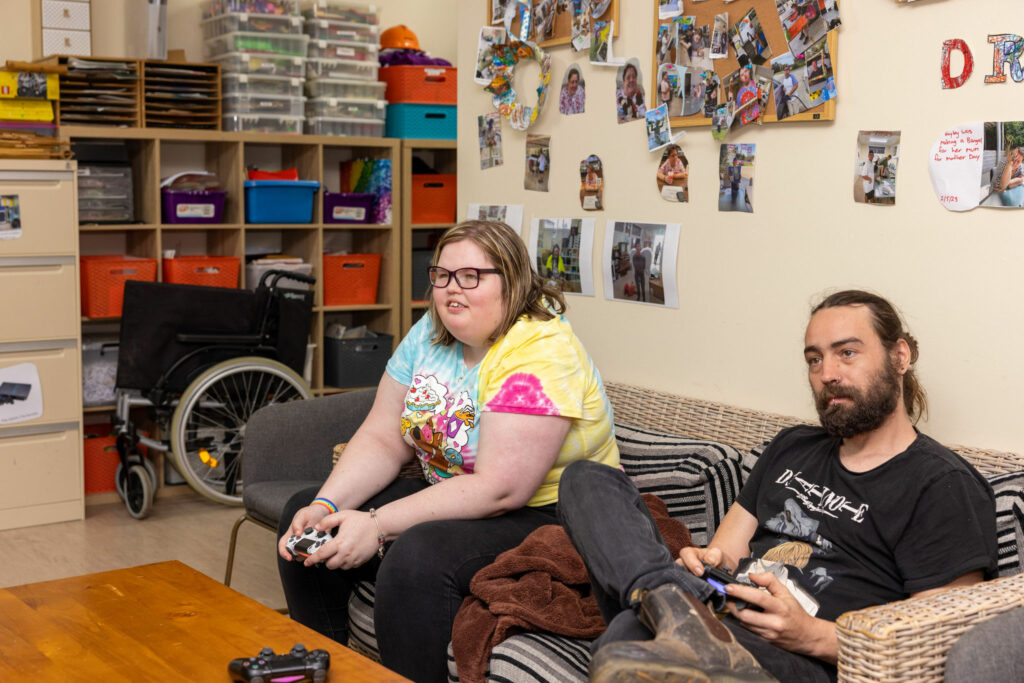 Gaming Group participant playing the PlayStation alongside Disability Support Worker